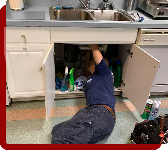 plumber doing repairs under kitchen sink